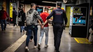 Un mosso de paisà i un uniformat senduen un detingut al metro de Barcelona en el marc del macrodispositiu Kanpai
