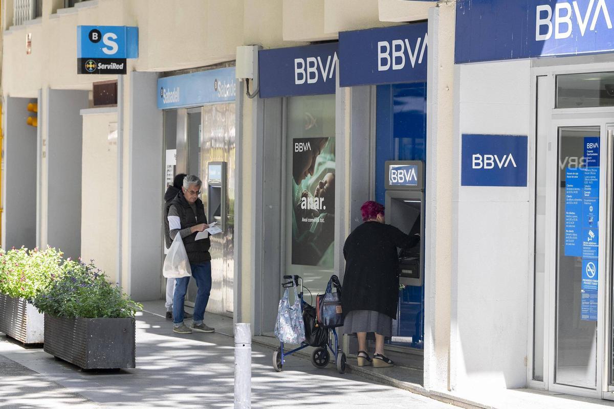 Clients utilitzant els caixers en oficines de BBVA i Sabadell.