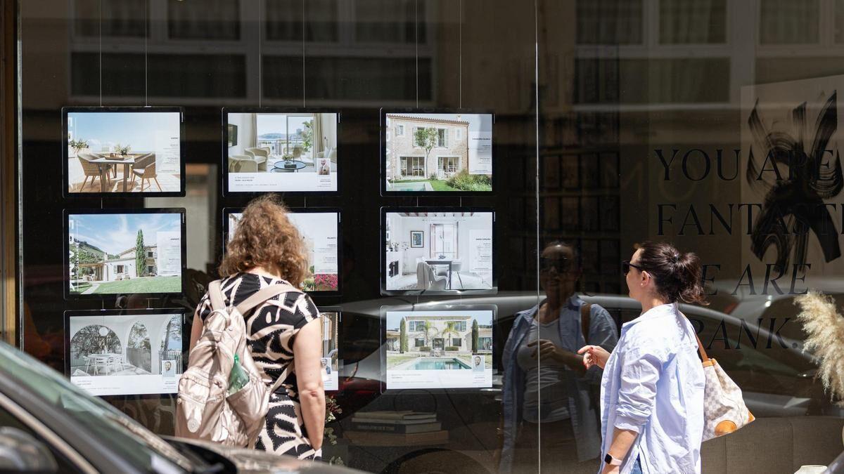 Dos personas observan los anuncios de viviendas en venta en una inmobiliaria.