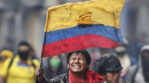 Un manifestante muestra la bandera de Ecuador en medio de una protesta.