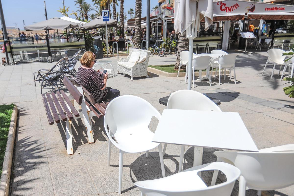Las mesas y sillas rodean un banco público del paseo de Juan Aparicio en Torrevieja