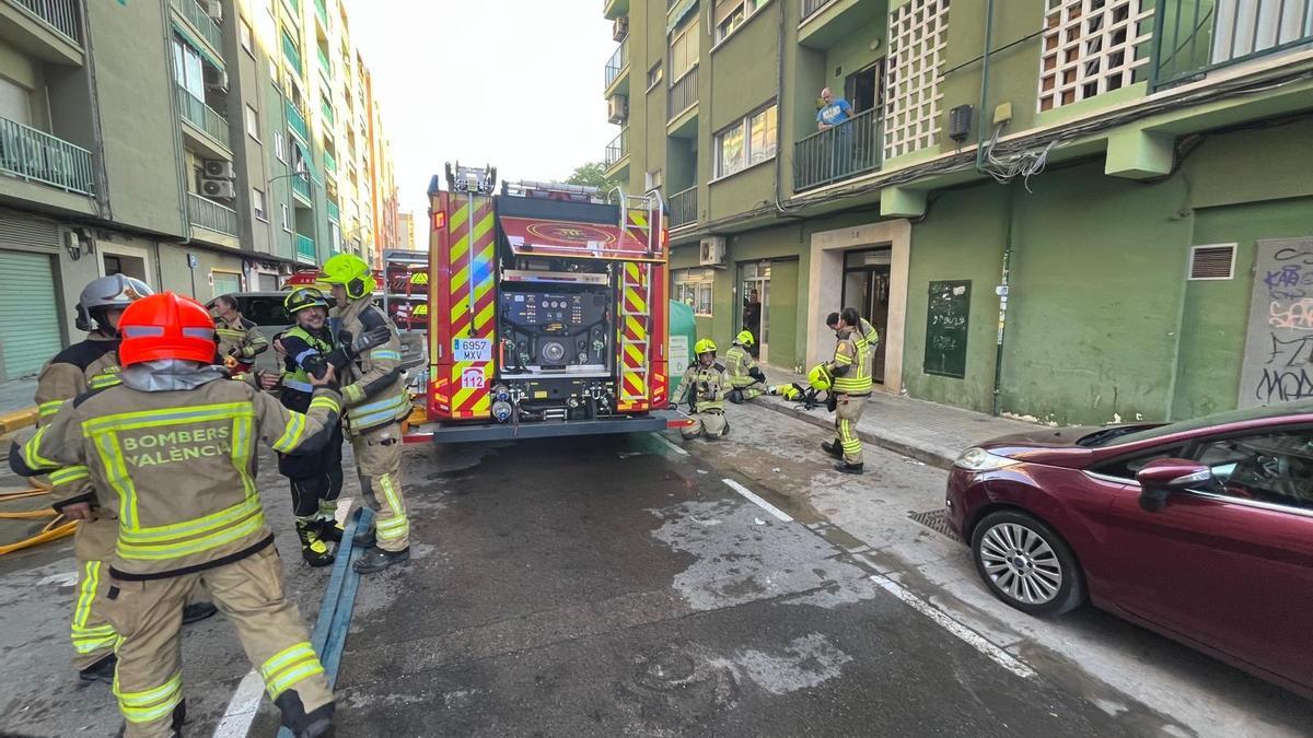 Los bomberos trabajando en la extinción del fuego en esta planta baja de València.