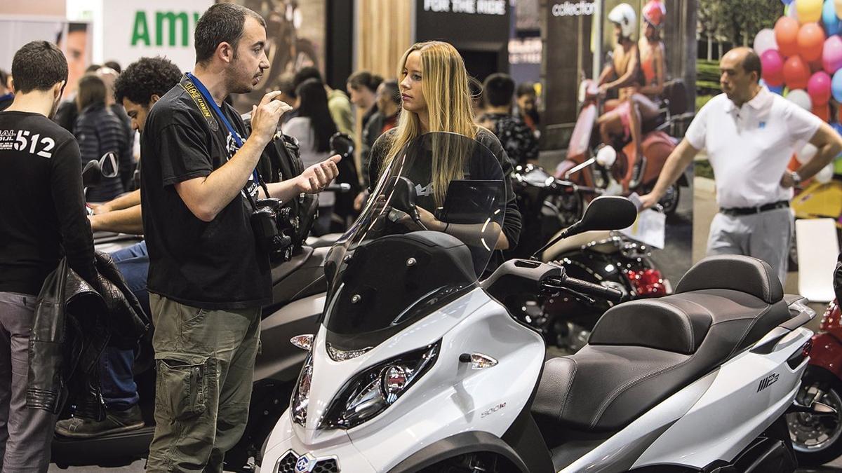 Un especialista comenta las ventajas de una moto de tres ruedas con una visitante de la pasada edición de Vive la Moto