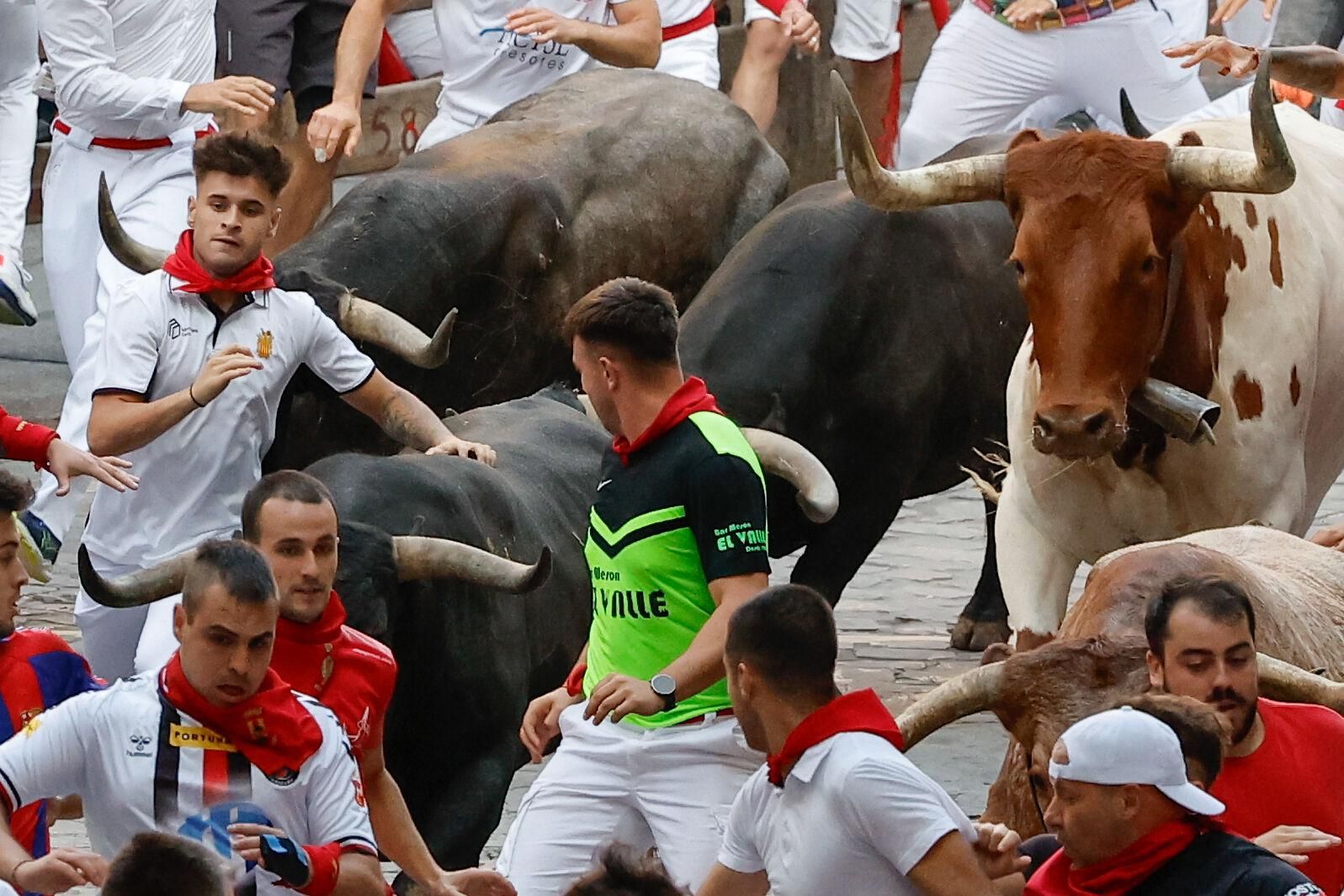PAMPLONA, 14/07/2025.- Los mozos son perseguidos por toros de la ganadería sevillana de Miura durante el octavo y último encierro de los Sanfermines este lunes. EFE/ Villar López