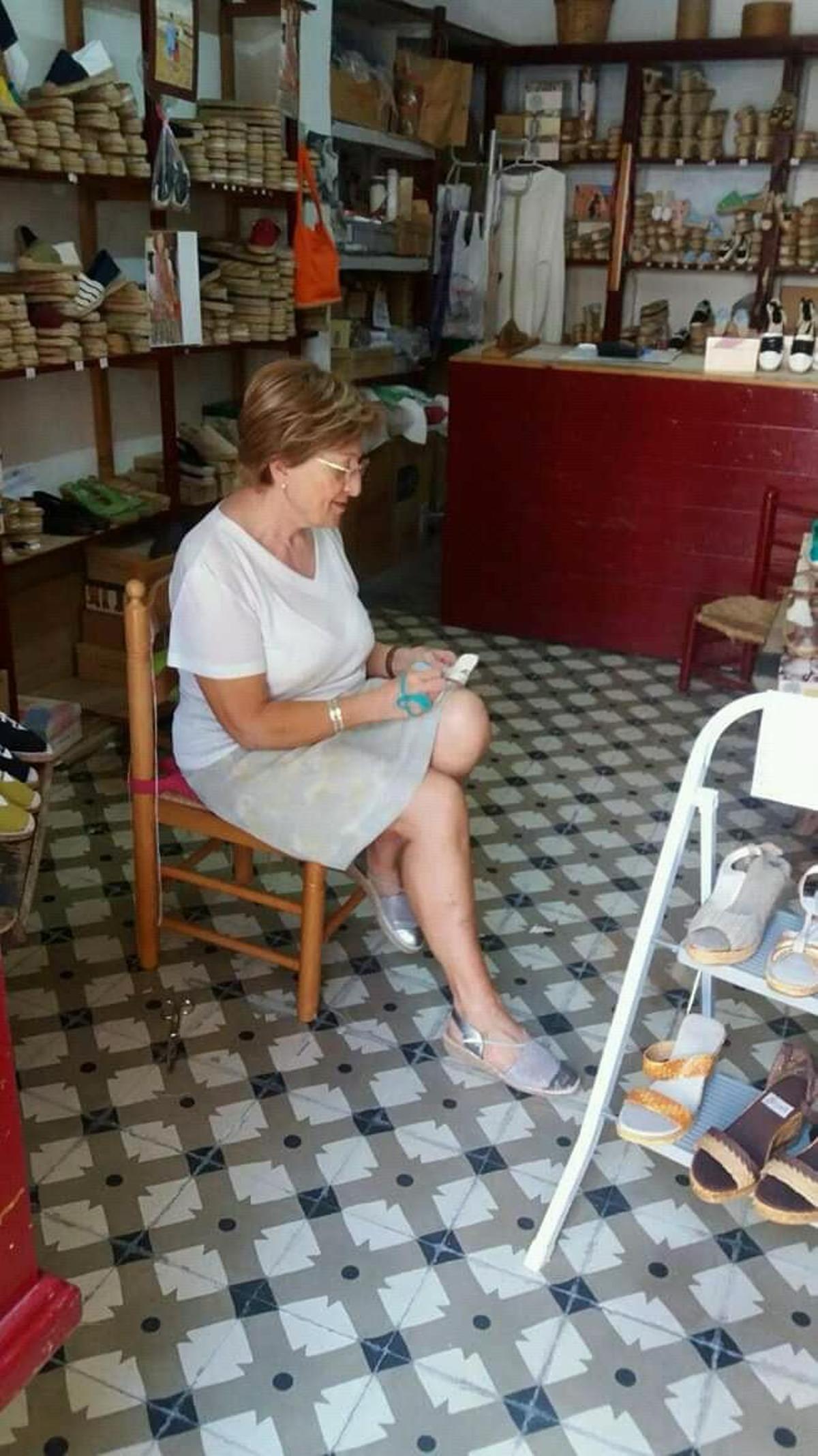 Marisa, cosiendo las telas de las alpargatas en su comercio.