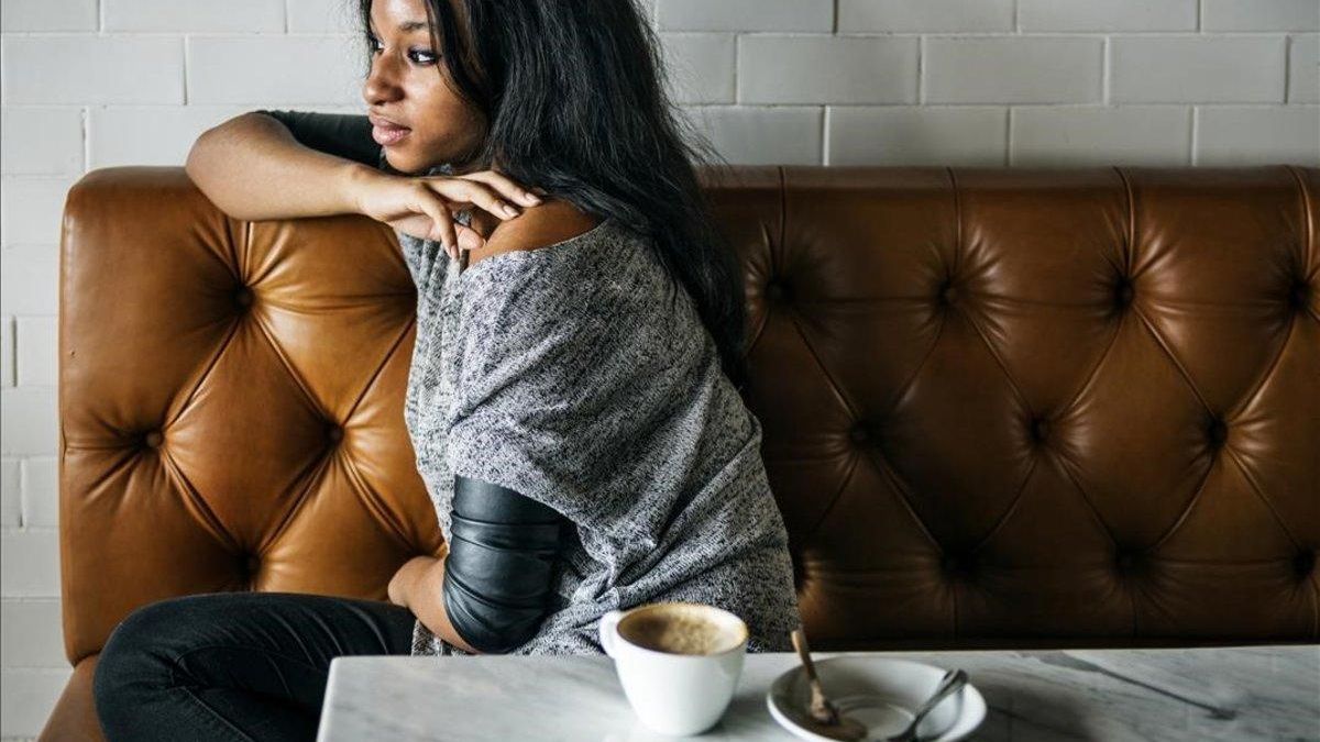 Una chica toma un café sentada en el sofá