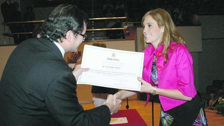 Sara López estrecha la mano del secretario general de Universidades, Màrius Rubiralta, al recoger su diploma.