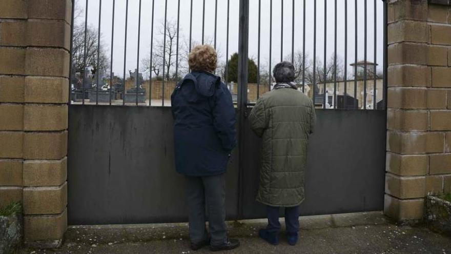 Dos personas observan el interior del cementerio de Formariz.