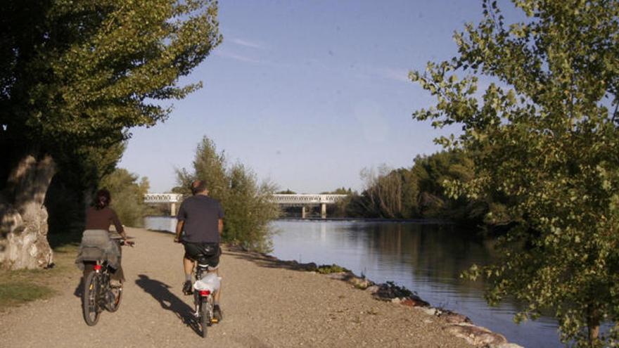 Dos personas pasean en bici junto al río Duero. |