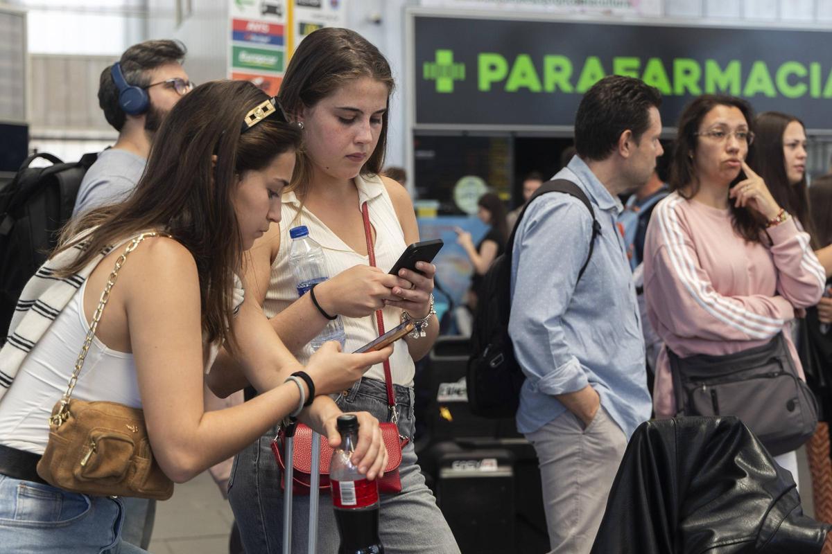 Dos jóvenes consultan el móvil ayer en la estación Joaquim Sorolla, afectadas por el apagón.