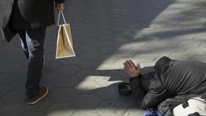 Una persona pide limosna en el Paseo de Gràcia de Barcelona.  