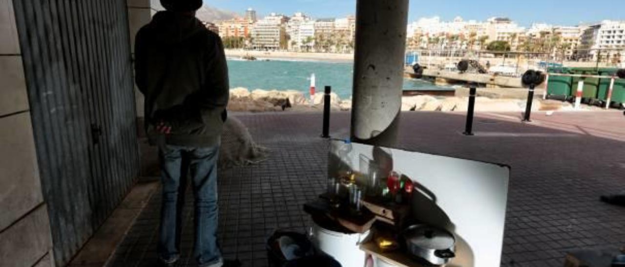 Una persona sin hogar mira al mar en el puerto de Benidorm.