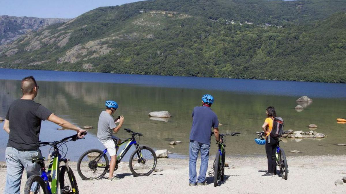 Un grupo de personas en bicicleta en una de las playas del Lago de Sanabria. | M. L. (ARCHIVO)