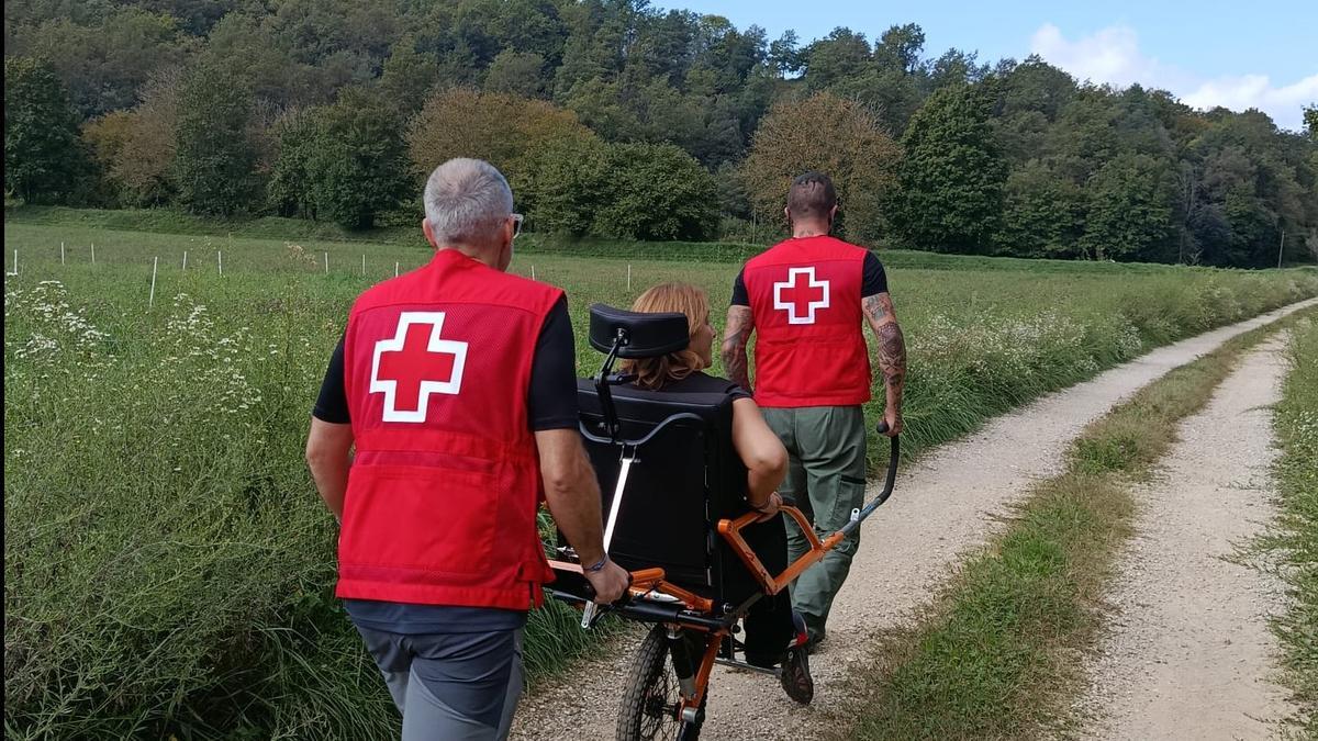 Dos voluntaris portant una usuària amb la cadira Joëlette.