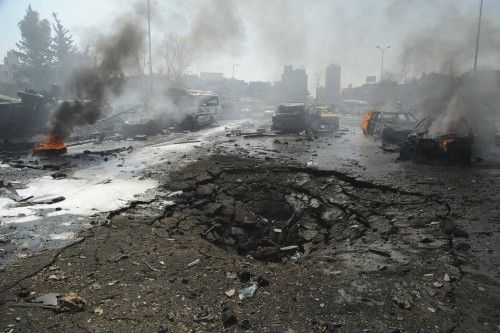 Coches ardiendo cerca de un cráter en la carretera tras una explosión en el centro de Damasco