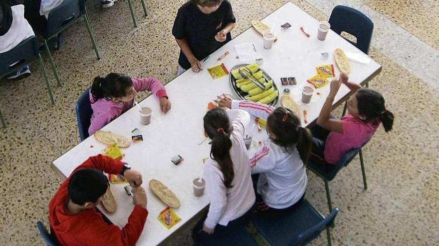 Varios niños comen en torno a una mesa.