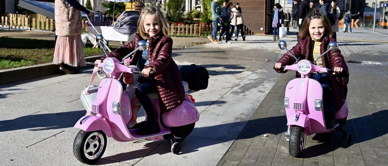Dos niñas disfrutan del Día de Reyes con sus motocicletas en la Praza de España.   // RAFA VÁZQUEZ