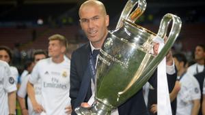 Real Madrids French coach Zinedine Zidane poses with the trophy after Real Madrid won the UEFA Champions League final football match between Real Madrid and Atletico Madrid at San Siro Stadium in Milan, on May 28, 2016. / AFP PHOTO / Filippo MONTEFORTE. HORIZONTAL