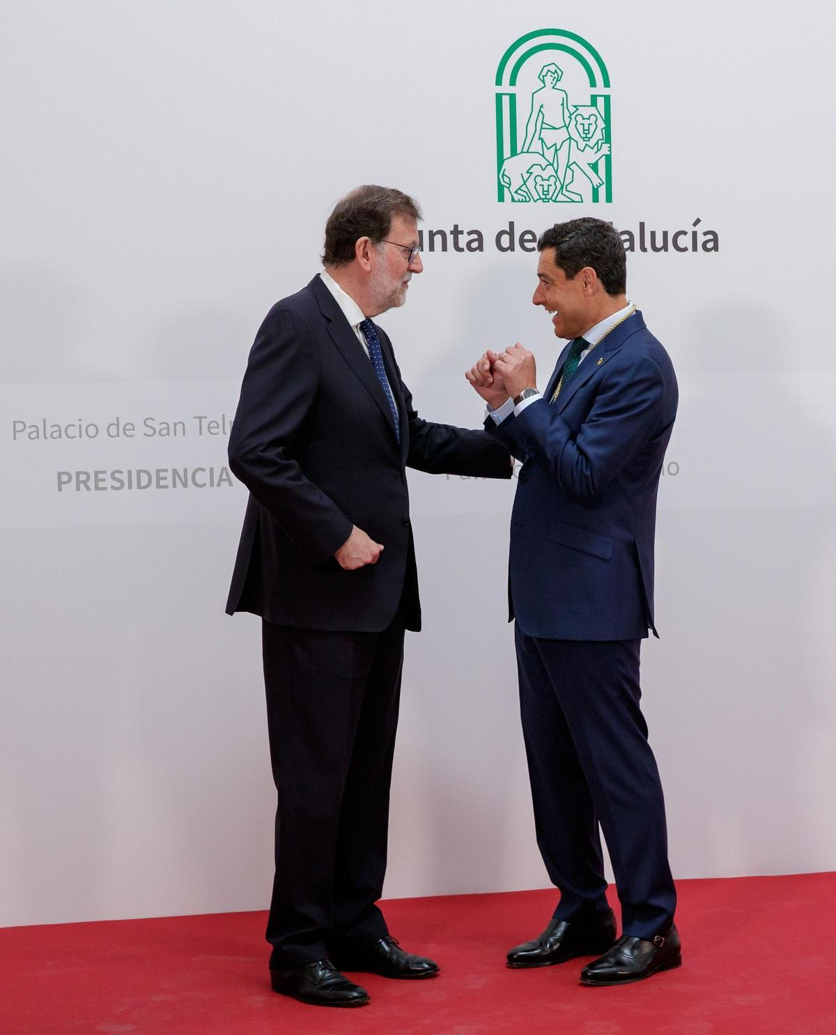 SEVILLA, 23/07/2022.- El presidente de la Junta de Andalucía, Juanma Moreno, y el expresidente del Gobierno, Mariano Rajoy, conversando hoy sábado tras jurar el cargo para un nuevo mandato en un acto que se ha desarrollado ante la fachada del Palacio de San Telmo de Sevilla, sede de la Presidencia. EFE/Julio Muñoz