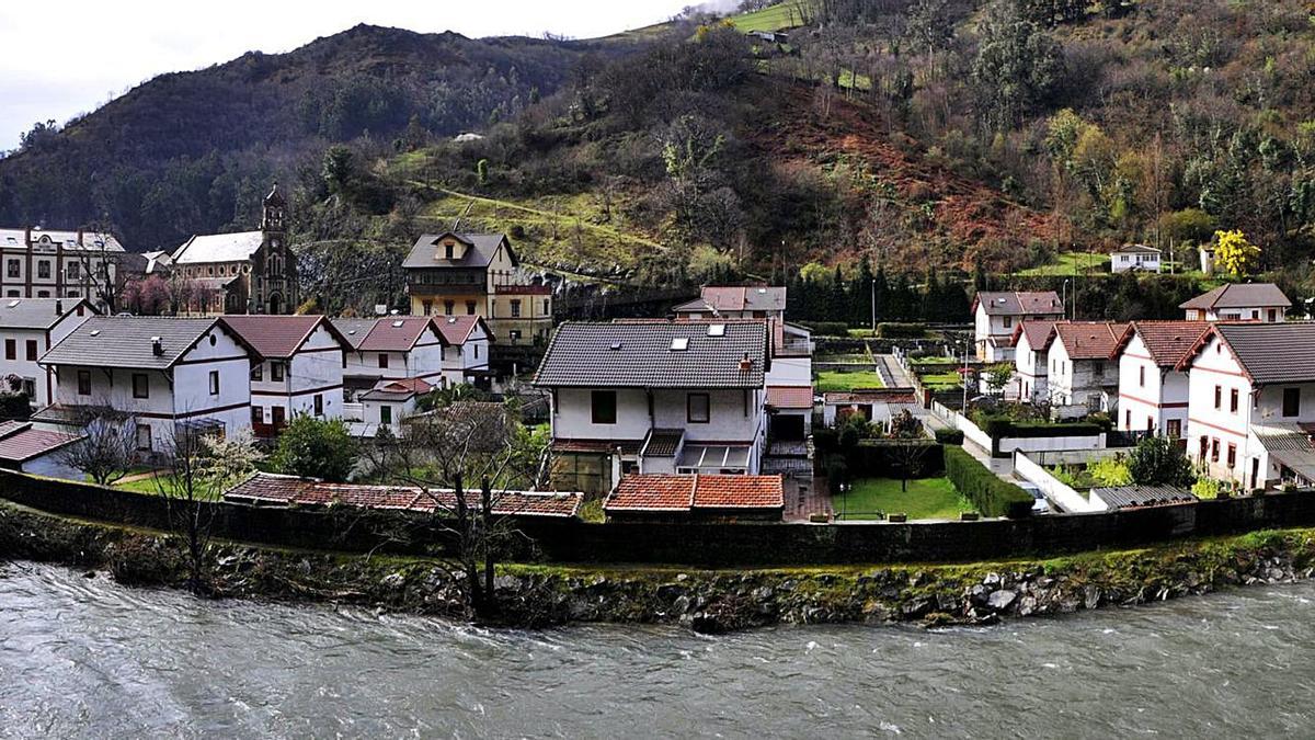 El poblado minero Bustiello, visto desde la orilla del río Aller por la que transita el trazado férreo.