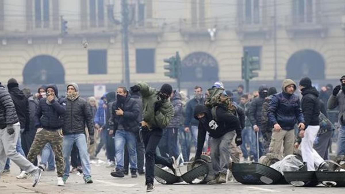 Un manifestante lanza una piedra en la protesta en el centro de Turín, este lunes.