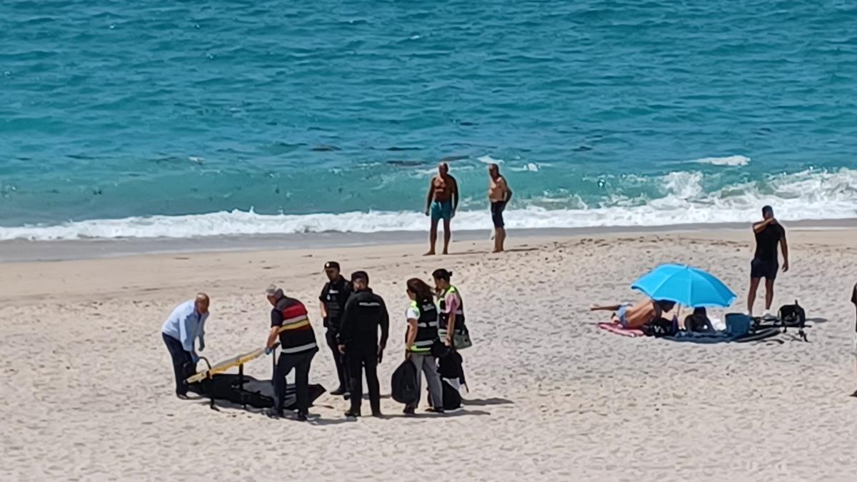 Sanitarios y agentes en la playa del Orzán con el cuerpo del fallecido en la arena.