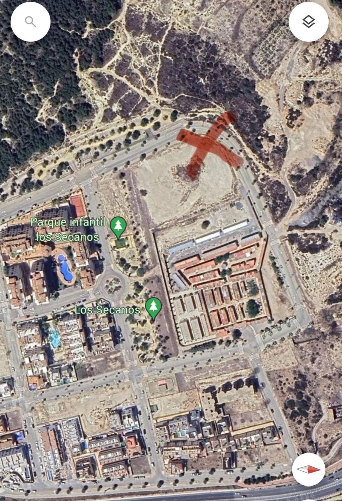 La cruz marca la ubicación en el extremo de la parcela más alejado del cementerio y las viviendas