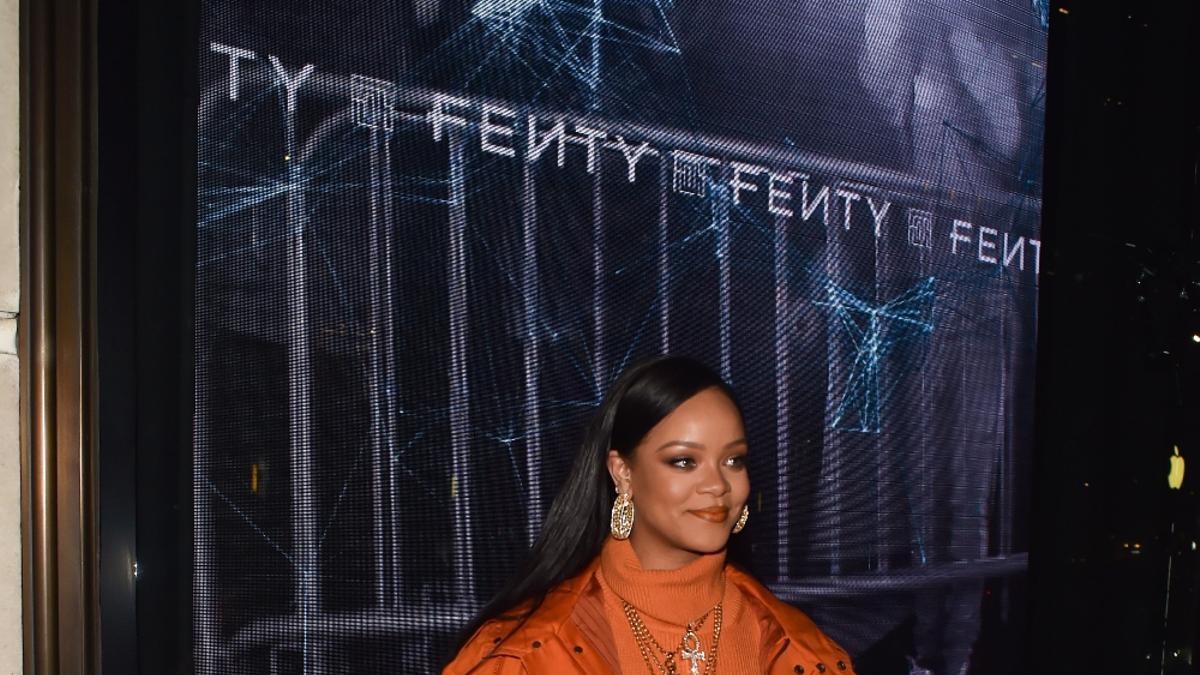 Rihanna con look en naranja en una tienda pop up de Fenty