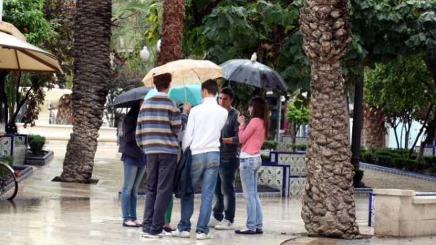 Jóvenes con paraguas, ayer en el centro de Elche.