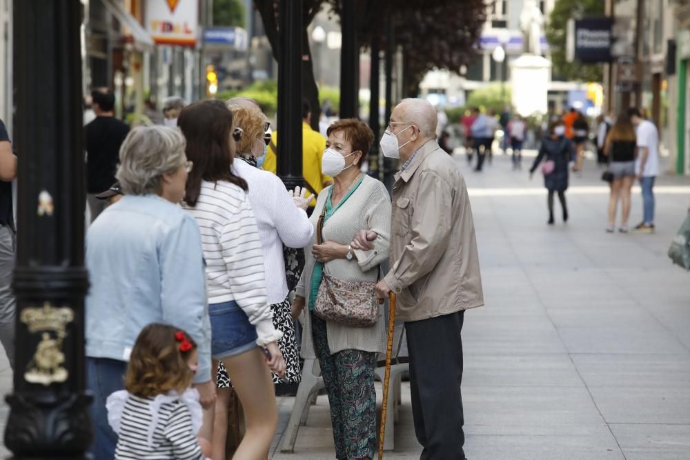 Gente con mascarilla y sin ella por el centro de Gijón.