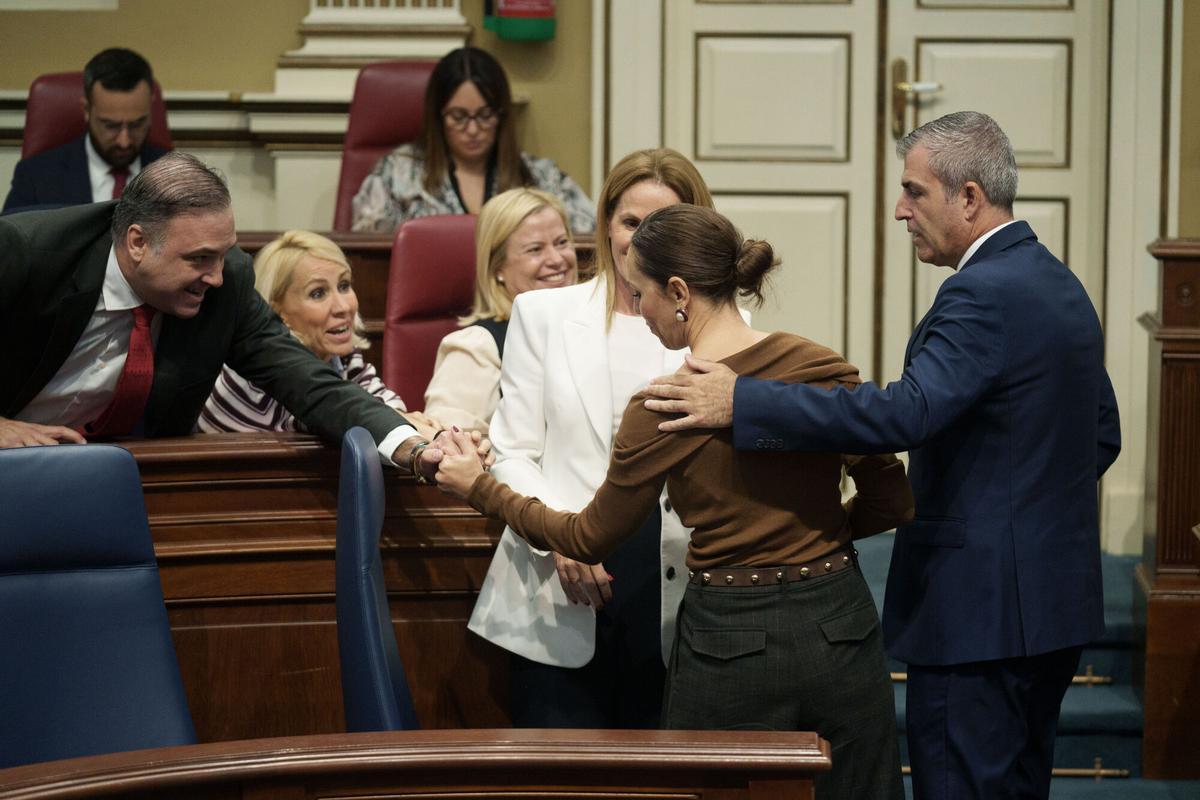 El pleno del Parlamento de Canarias ha aprobado este miércoles, sin consenso, la ley que regula el uso turístico de la vivienda, una norma con medidas para frenar la sustitución masiva de viviendas residenciales por viviendas de alquiler turístico. En la imagen, el vicepresidente del Gobierno de Canarias, Manuel Domínguez (1d), y varios diputados del PP felicitan a la consejera de Turismo, su compañera Jéssica de León (2d), durante el debate.
