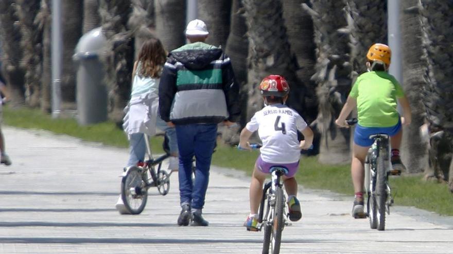 Niños pasean en bicicleta acompañados de su padre en La Malagueta.