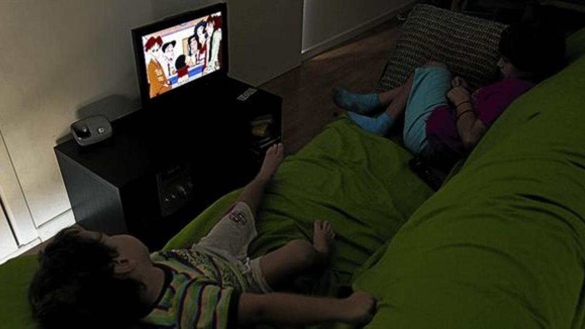 Dos niños miran un capítulo de una serie de dibujos animados en la televisión, ayer.
