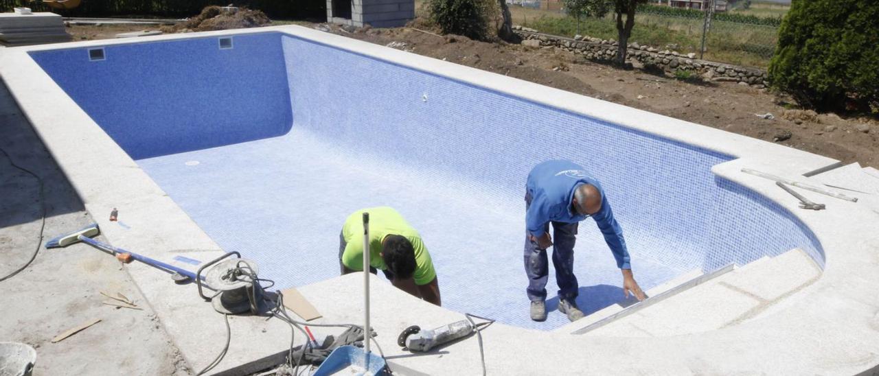 Operarios trabajan en el acabado de una piscina en la comarca.