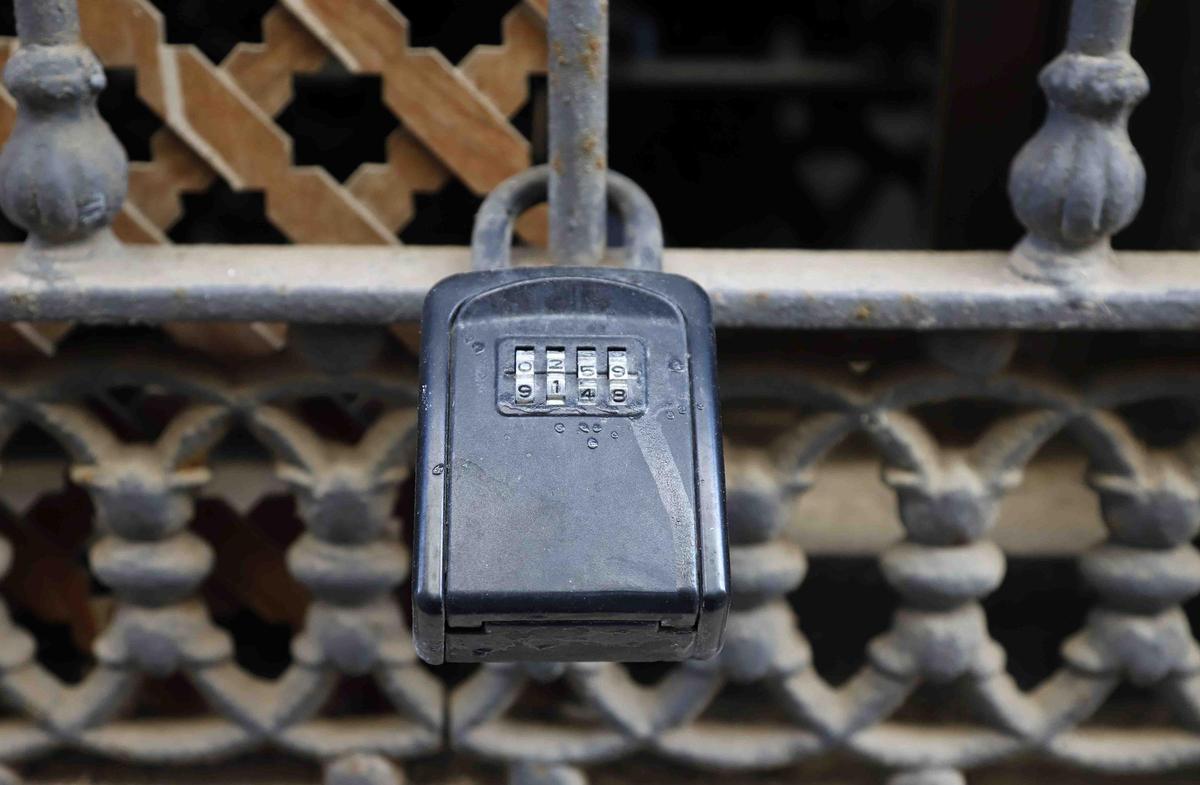Varios turistas pasan cerca de cajas o cajetillas de llaves de los pisos turísticos que hay en el casco histórico de Málaga.