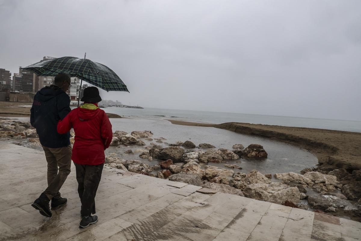 Dos personas observando los efectos de las lluvias en la playa de la Albufereta, en Alicante, hace unos días.