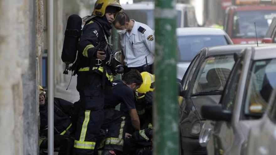 Los servicios sanitarios trasladan a uno de los bomberos afectados que resultó intoxicado ayer tarde en el incendio de un bar.