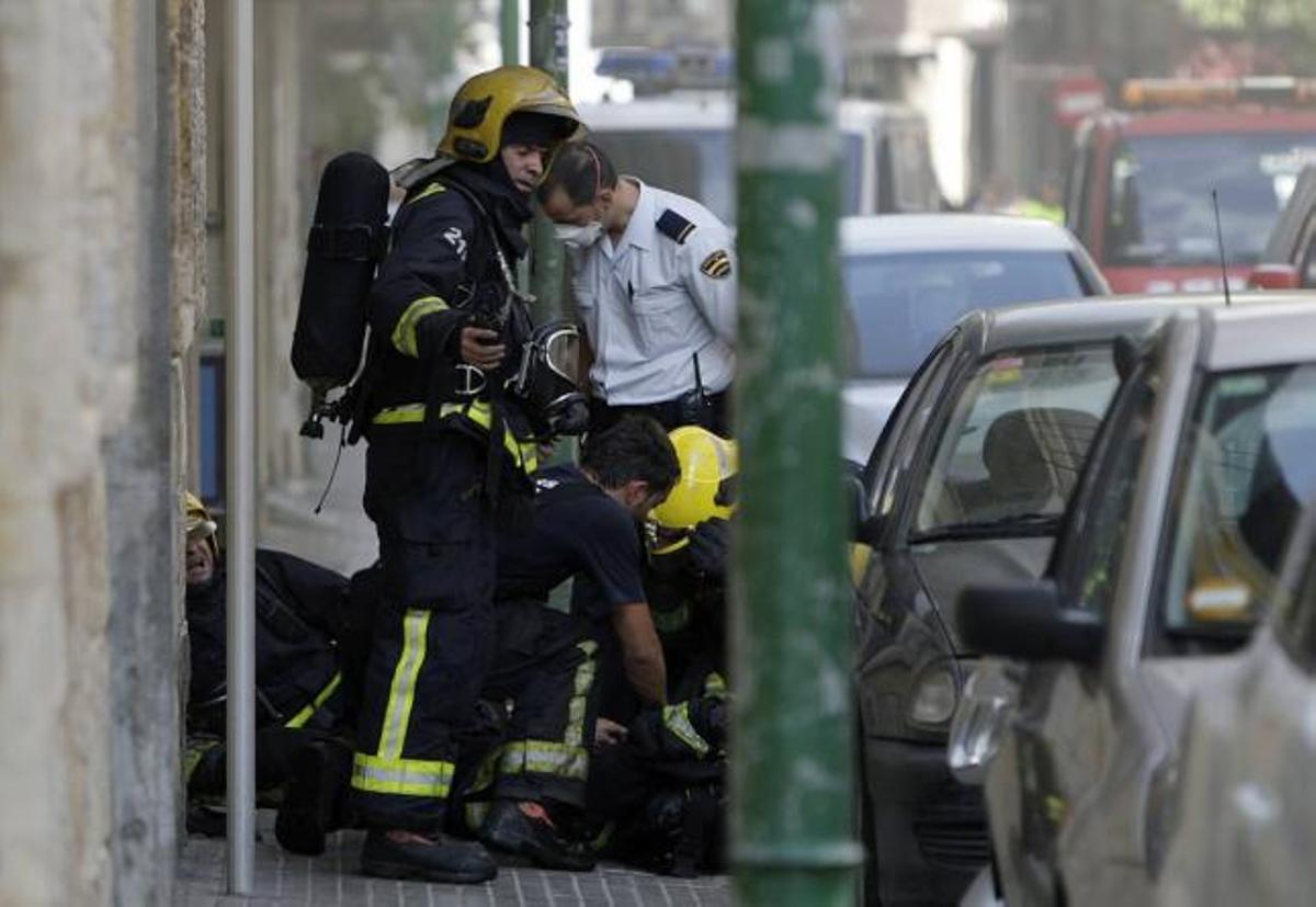 Los servicios sanitarios trasladan a uno de los bomberos afectados que resultó intoxicado ayer tarde en el incendio de un bar.