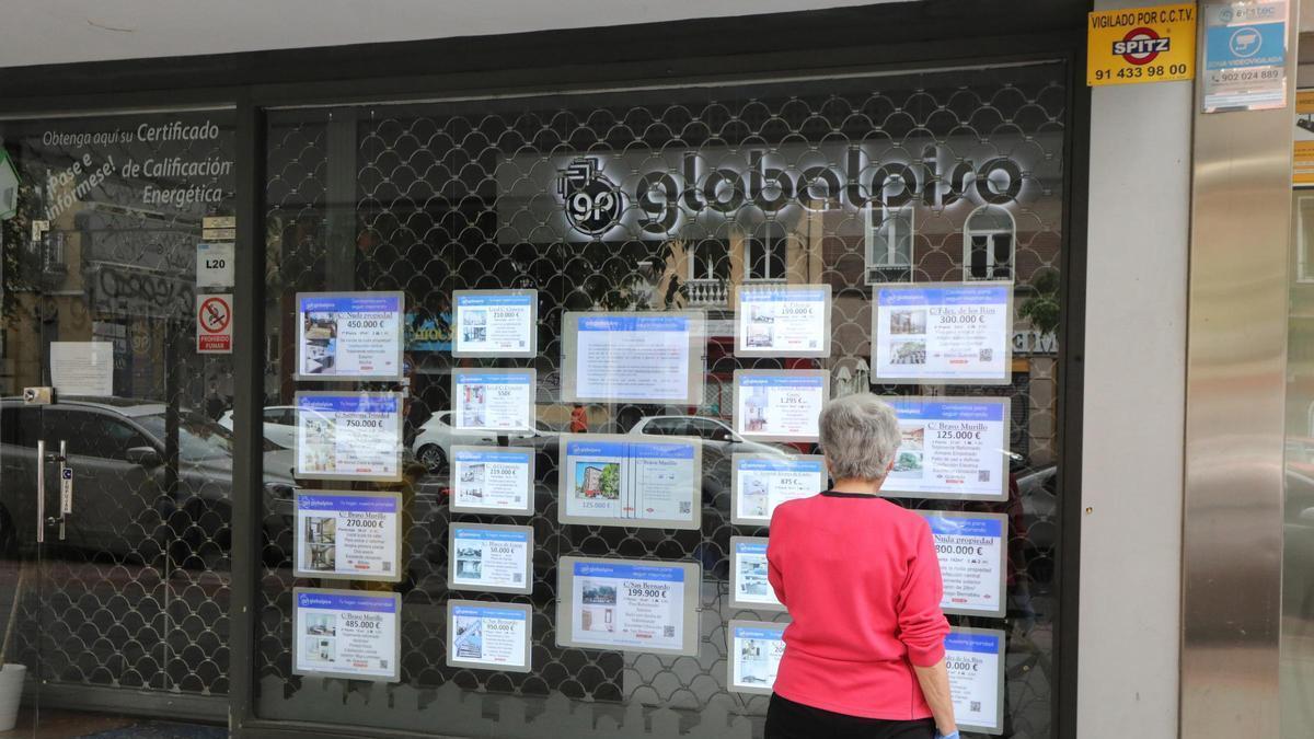 Una mujer echa un vistazo a las ofertas de una agencia inmobiliaria.