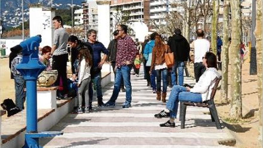 Diverses persones passejant pel passeig marítim de Palamós.