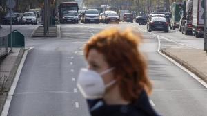 Una mujer con mascarilla pasa frente a los coches en la Gran Via de Barcelona.