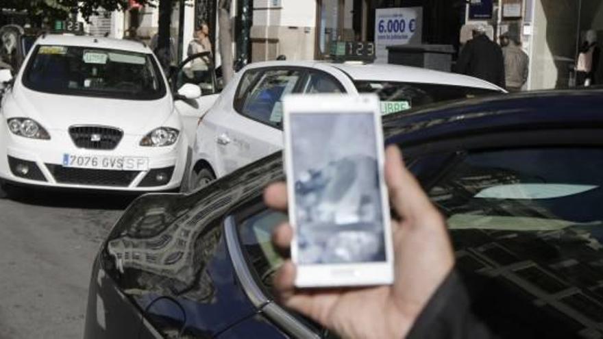 Un chófer de Cabify muestra la aplicación en la calle, junto a un taxista, en una imagen de archivo.