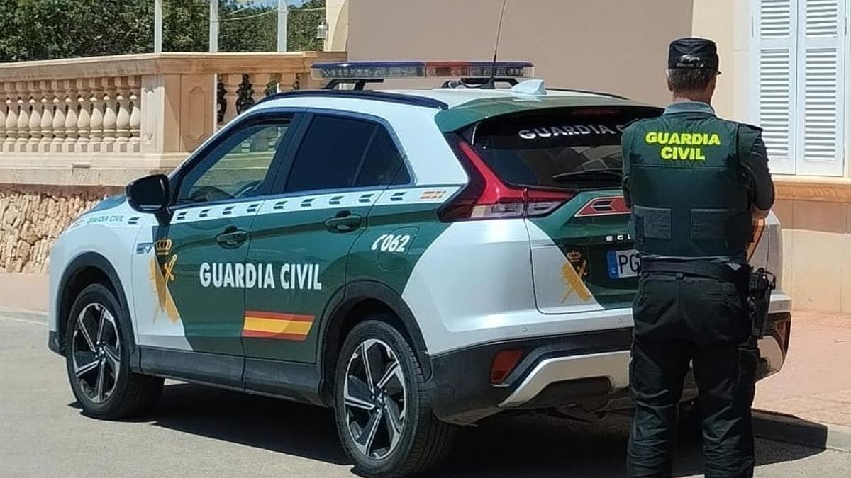Un agente de la Guardia Civil junto a su coche patrulla.