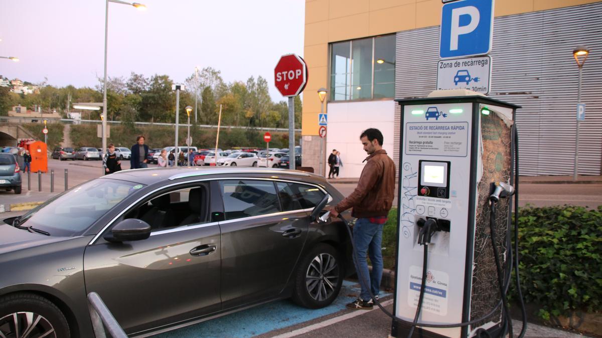 Un home carregant el seu vehicle híbrid a l'únic carregador públic que queda a Girona, davant del Ocines