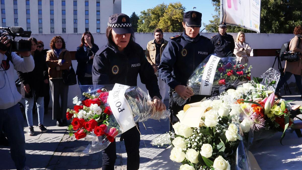 Dos policías colocan un ramo de flores en el monolito.