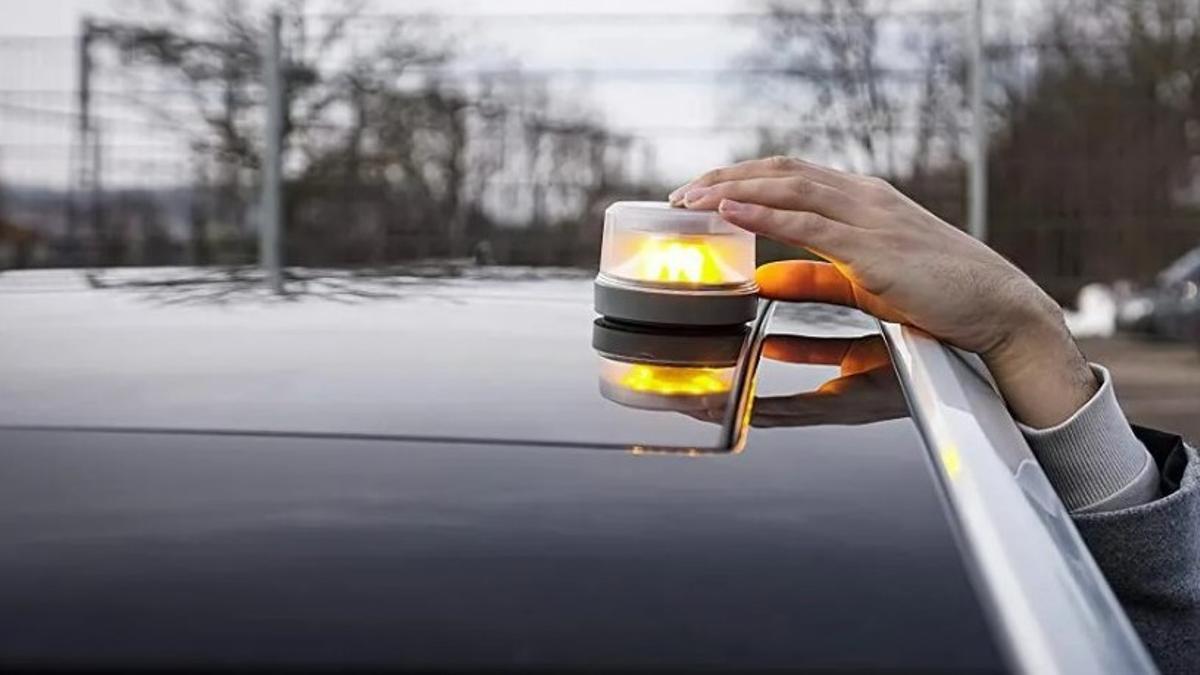 Un hombre coloca un dispositivo de señalización sobre el capó de un coche