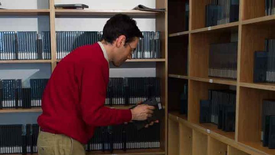 Un usuario de la Biblioteca municipal observa los títulos de una estantería de películas en DVD.