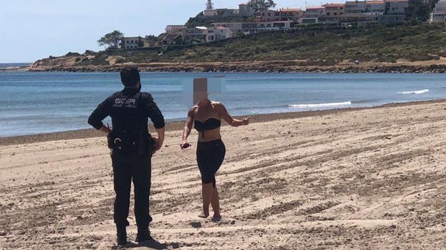 Un policía local junto a una mujer que estaba andando por la playa