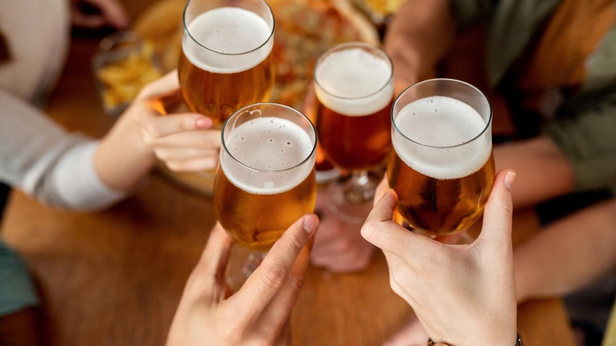 Varios amigos brindan con cerveza en un bar
