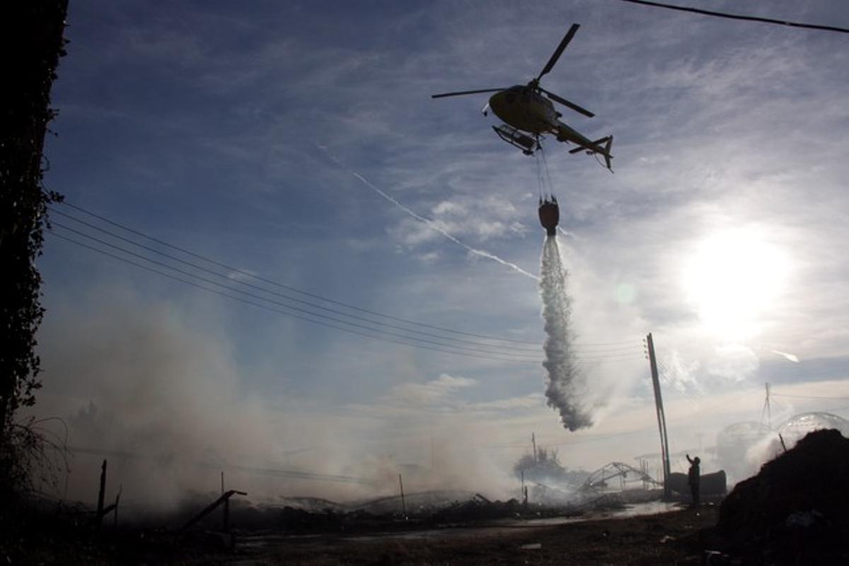 Un helicòpter de Bombers de la Generalitat tira aigua sobre les flames, aquest dijous.